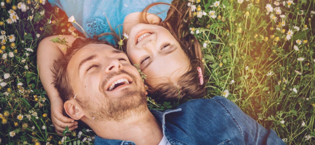 Vater und Tochter liegen im Gras.