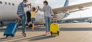 Junges Paar mit Kind und Koffern laufen zu einem Flugzeug.