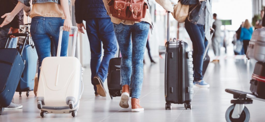 Passagiere laufen mit ihren Koffern durch einen Flughafen.