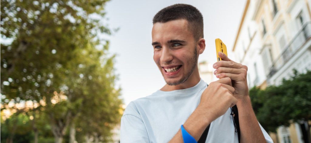 Blinder junger Mann draußen hält Smartphone in der Hand an sein Ohr