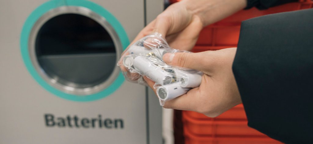 Person entsorgt Batterien in dafür vorgesehenen Müll