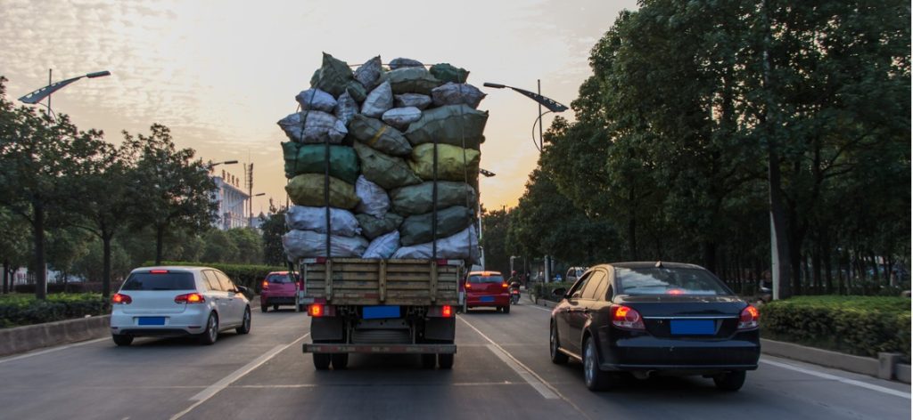 Autos und ein zu stark beladener Lkw auf einer dreispurigen Straße
