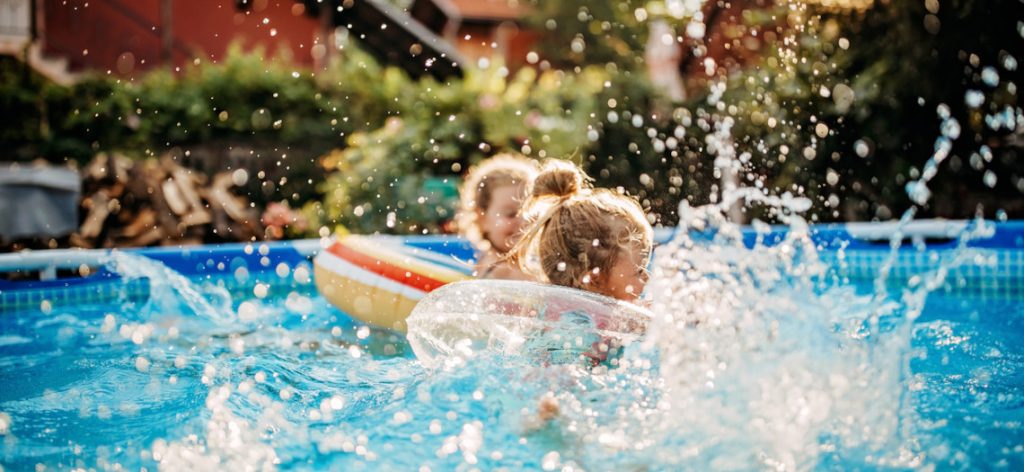 Kinder planschen mit Schwimmreifen im Pool im Garten