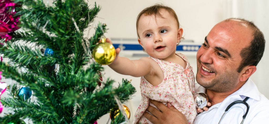 Arzt und Kleinkind schmücken Weihnachtsbaum
