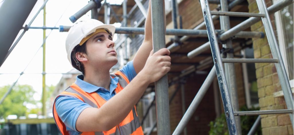 Bauarbeiter mit Warnweste und Helm auf einem Gerüst