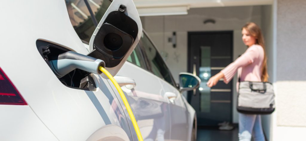 Weißes Elektroauto mit geöffnetem Tankdeckel aufladen