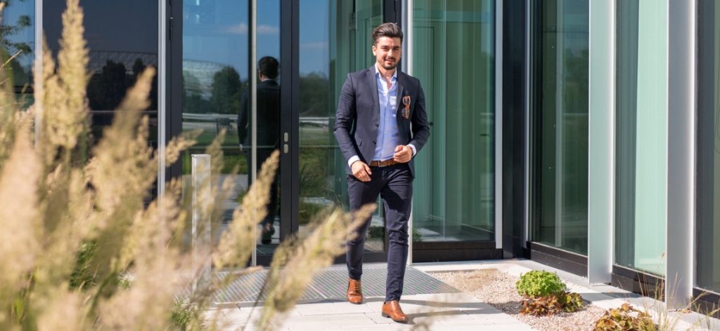 Businessmann in Anzug verlässt Bürogebäude bei Sonnenschein