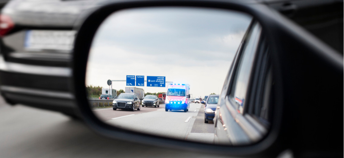 Rettungswagen im Seitenspiegel eines Autos auf der Autobahn