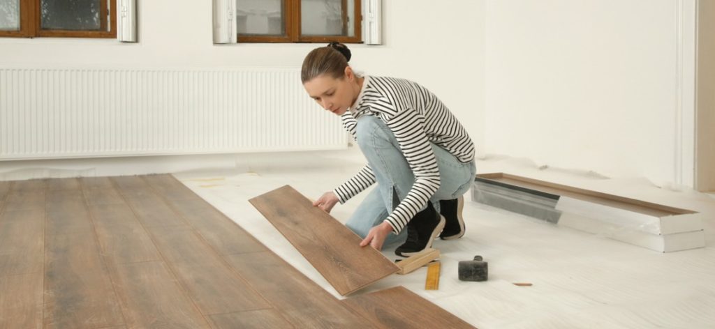 Junge Frau verlegt Holzfußboden in Wohnung