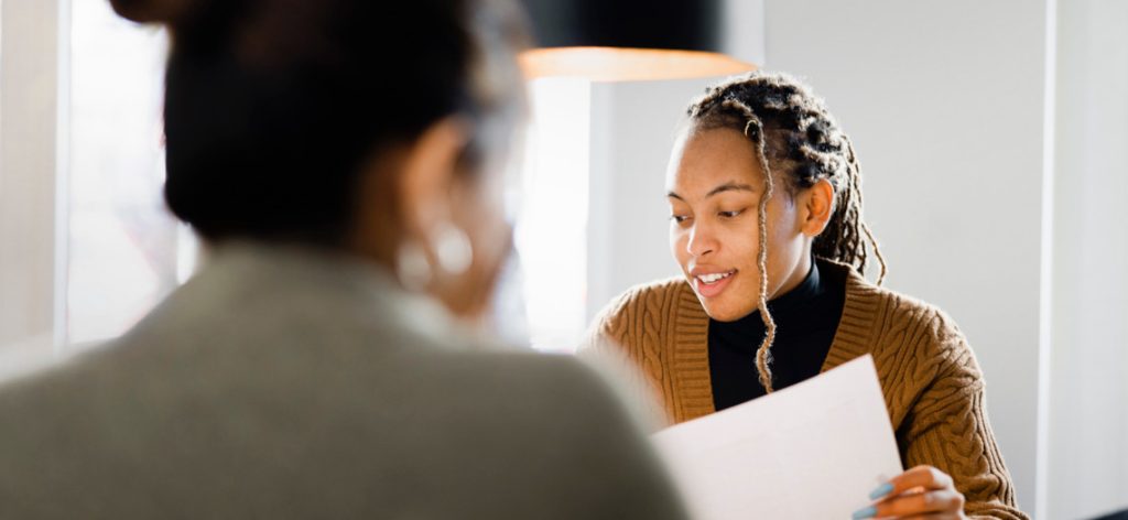 Bewerberin und Angestellte beim Vorstellungsgespräch am Tisch mit Dokumenten