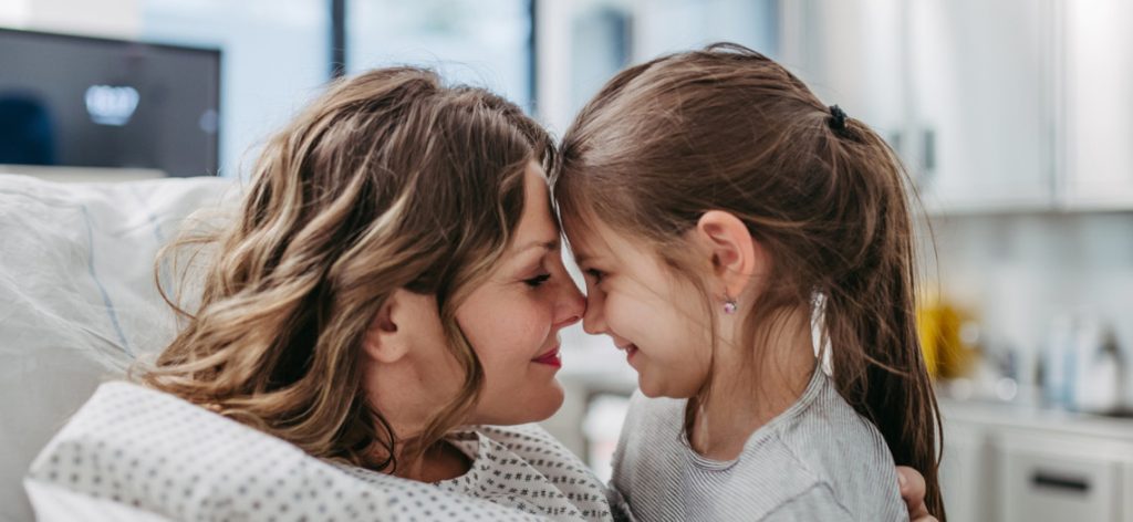 Mutter in Krankenhausbett umarmt Tochter