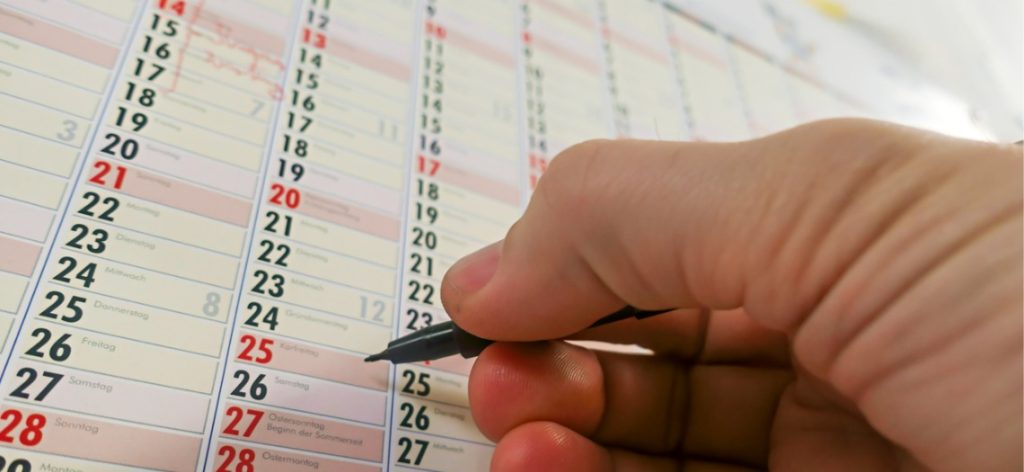 Hand hält Stift und schreibt etwas in den Kalander