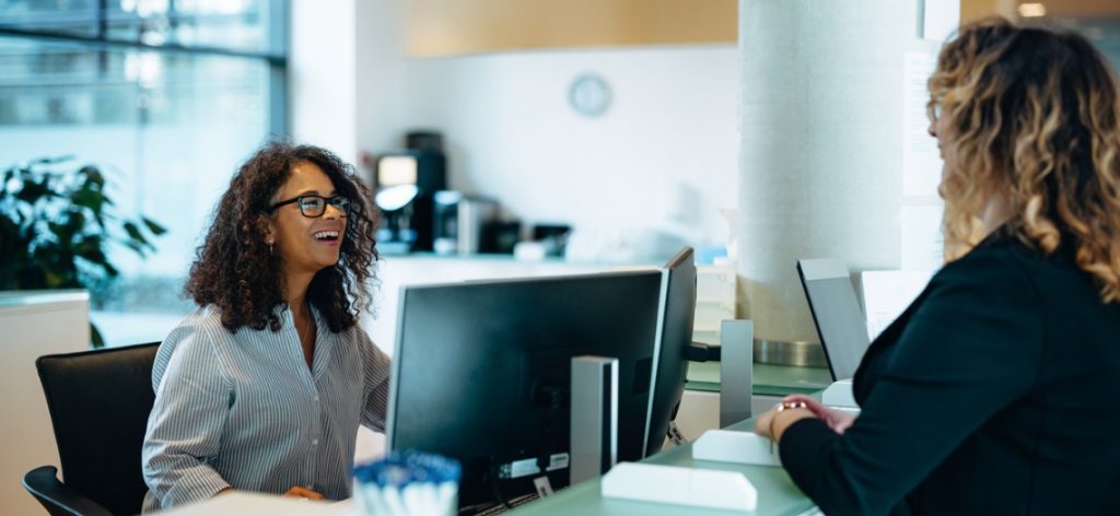 Zwei Frauen sitzen sich beim Amt lachend gegenüber