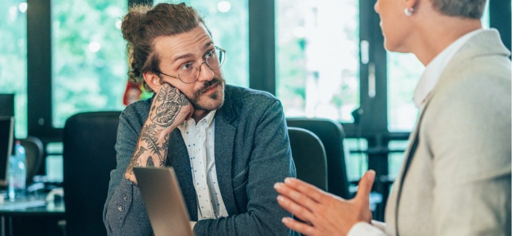 Mann mit Tattoos auf Arm und Hand in Vorstellungsgespräch mit Frau