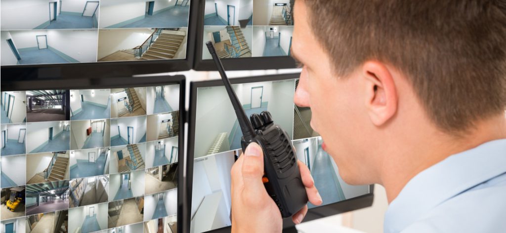 Security Mann überwacht mit Walkie Talkie Räume auf Monitor