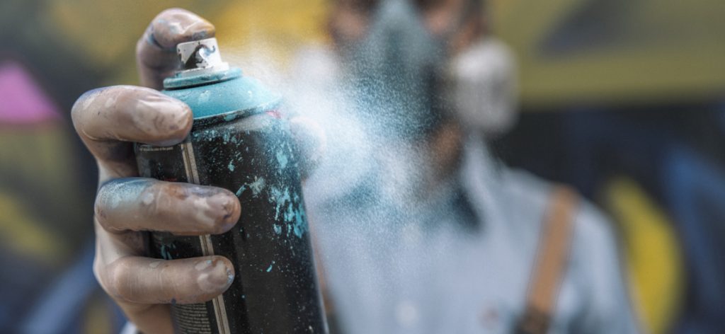 Graffitikünstler hält eine Sprühdose mit Farbe in der Hand