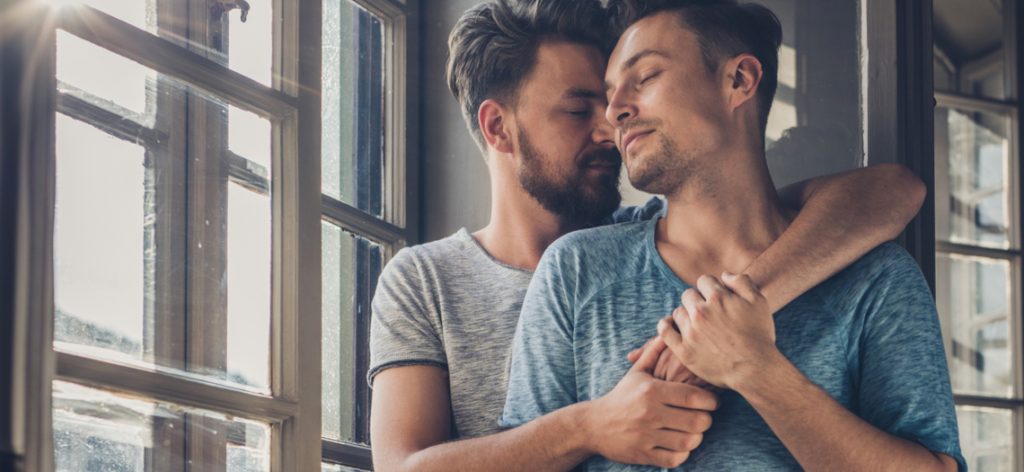 Affectionate homosexual couple enjoying in their love by the window.