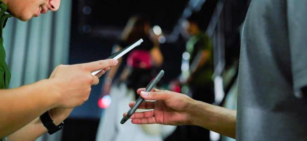 Zwei Personen halten ihr Smartphone nahe beieinander